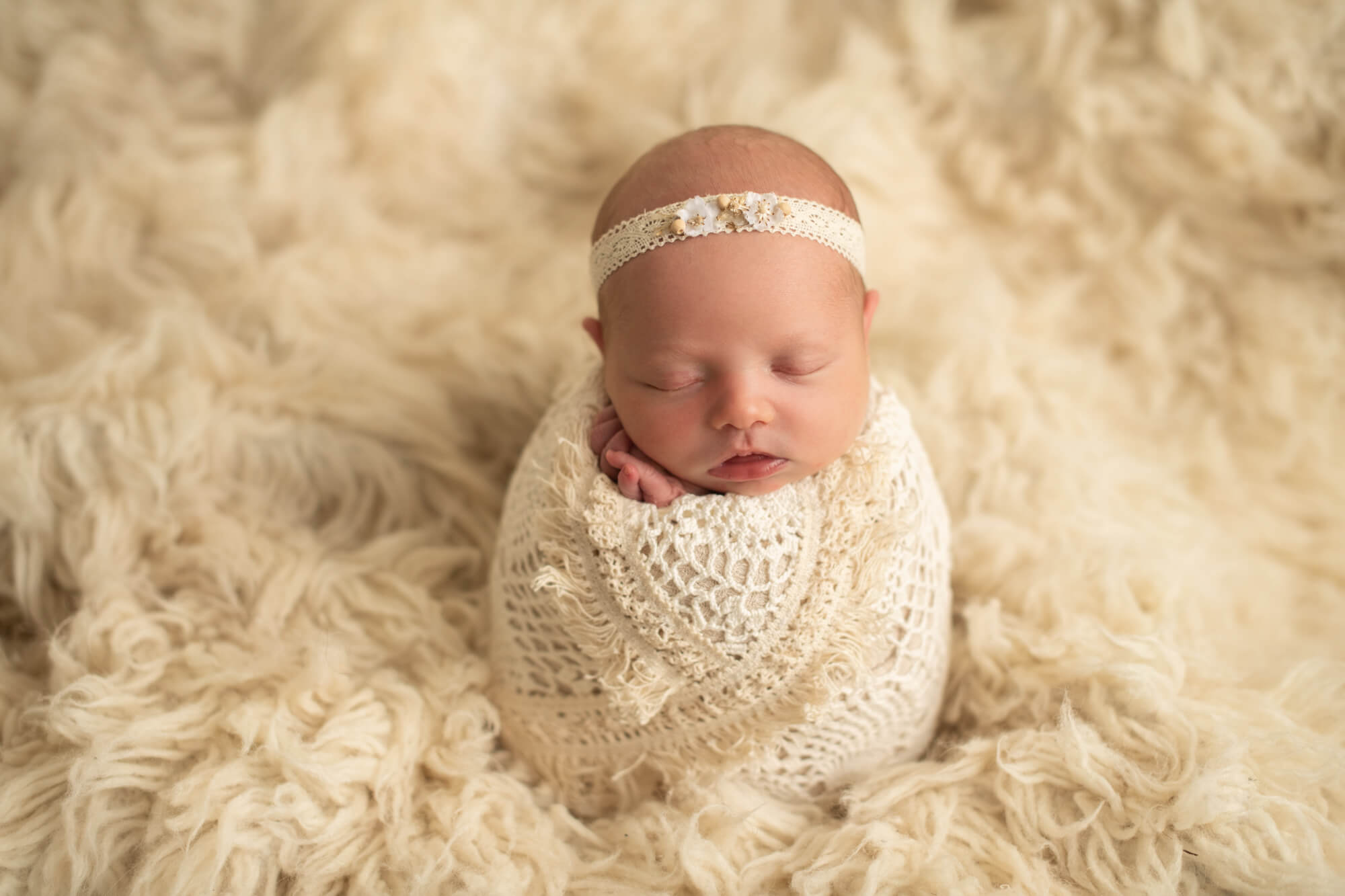 newborn baby wrapped in cream with a cream headband