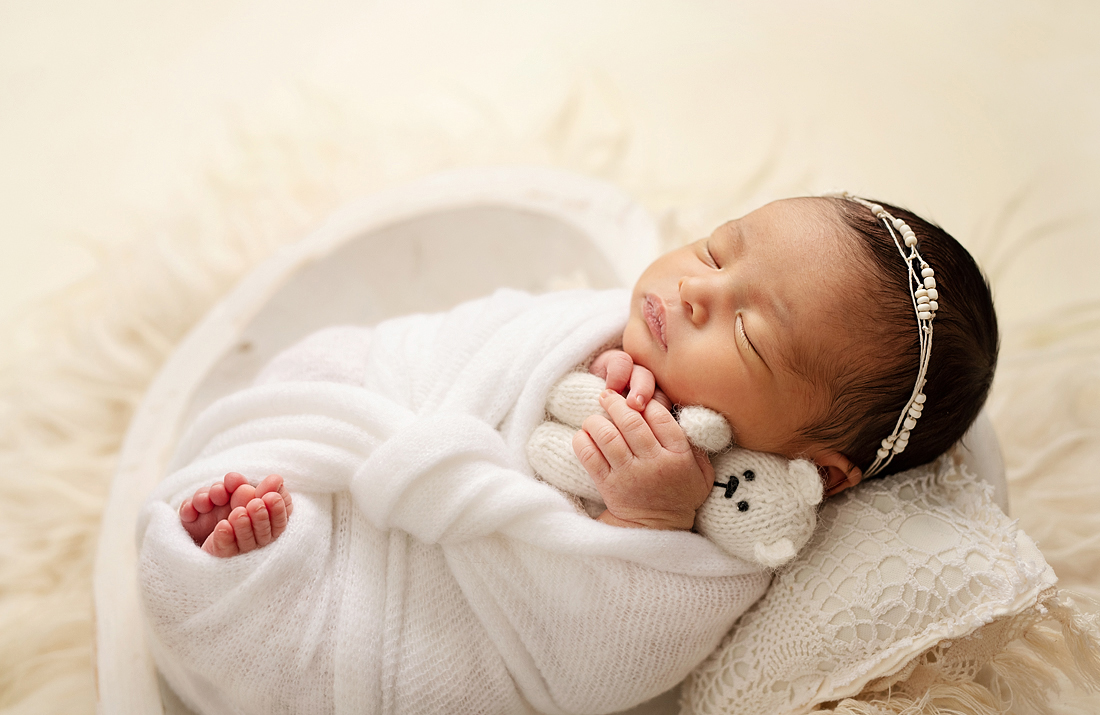 newborn girl in white wrap with cuddle bear Alberta Midwives