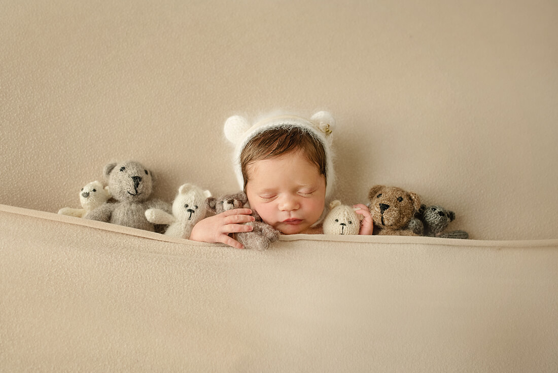 Newborn baby girl tucked in with stuffed animals