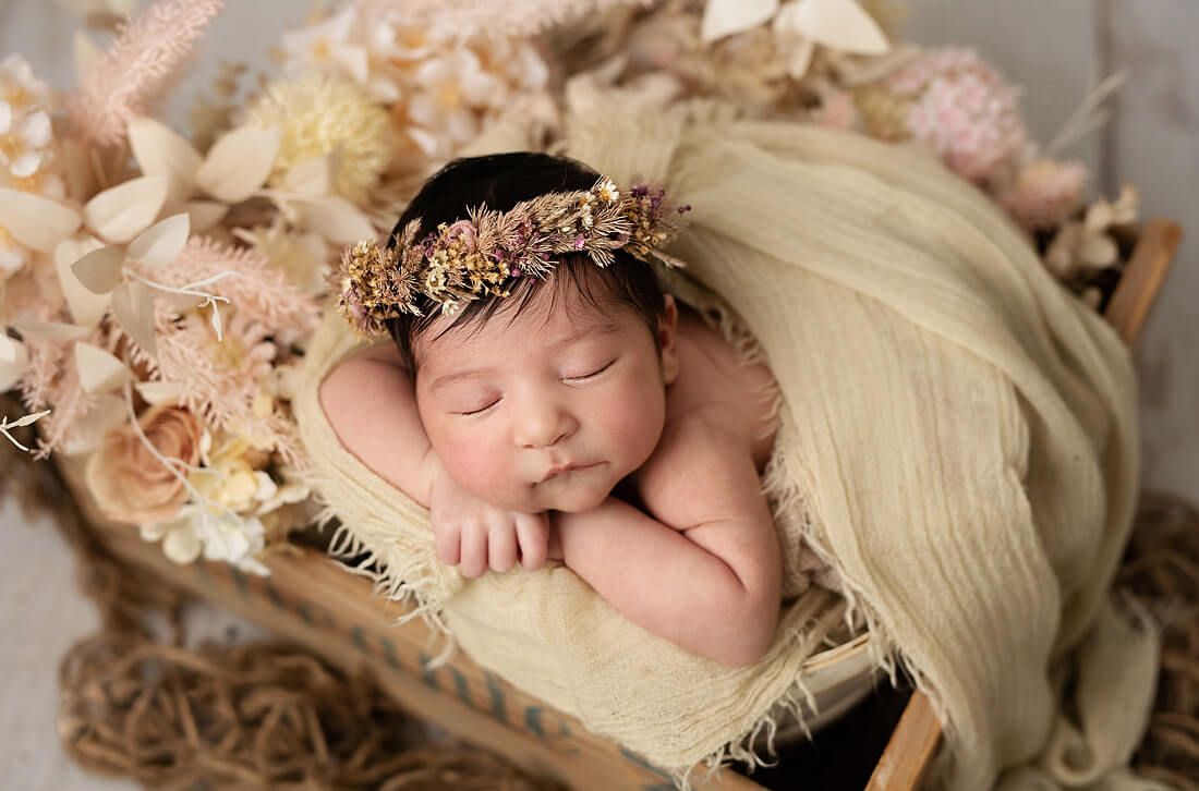 newborn baby girl in a box with neutral flowers