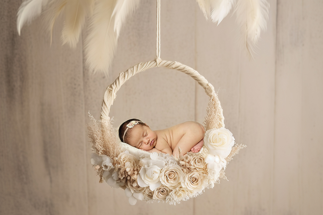newborn baby girl styled in bright boho circle with flowers and feathers Edmonton Prental Yoga
